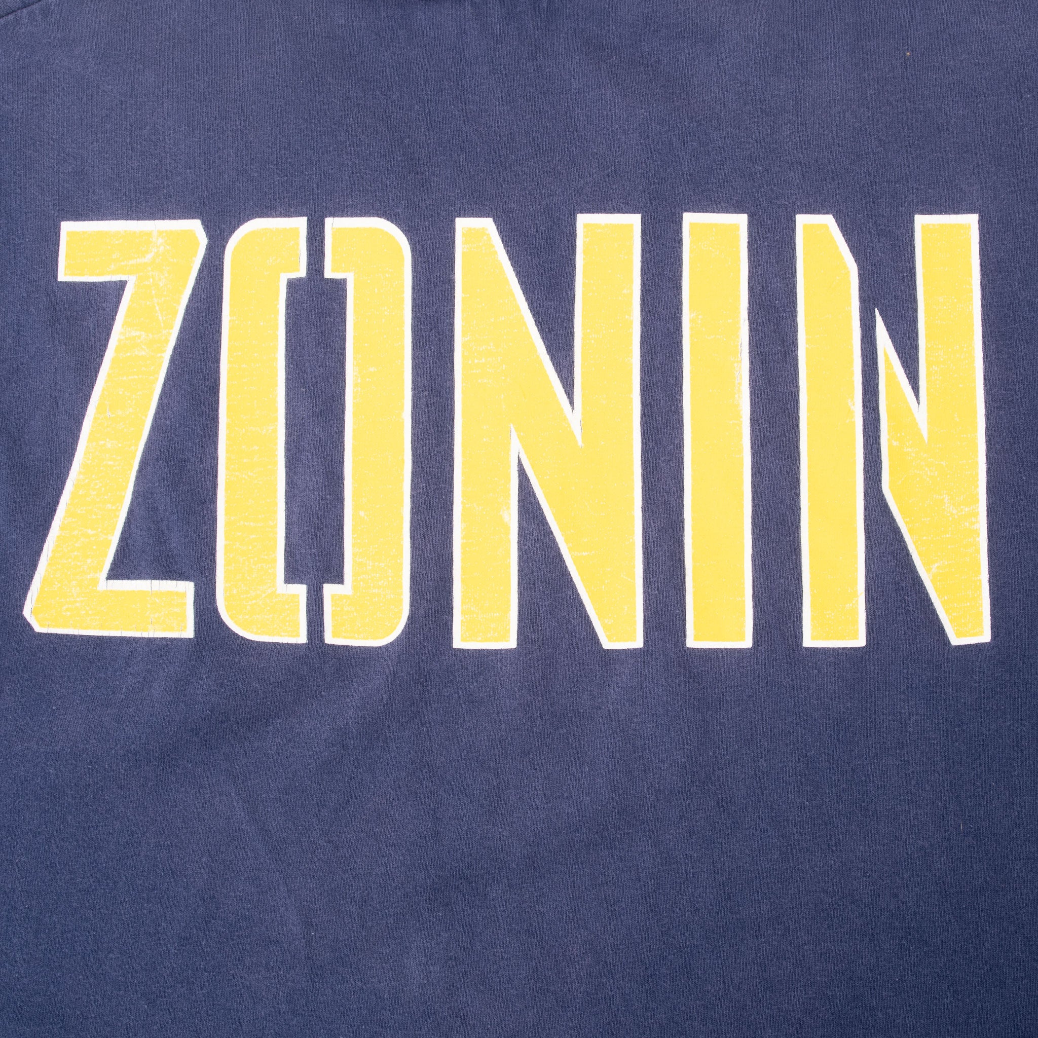Close-up of yellow Zonin back print outlined in white on navy fabric