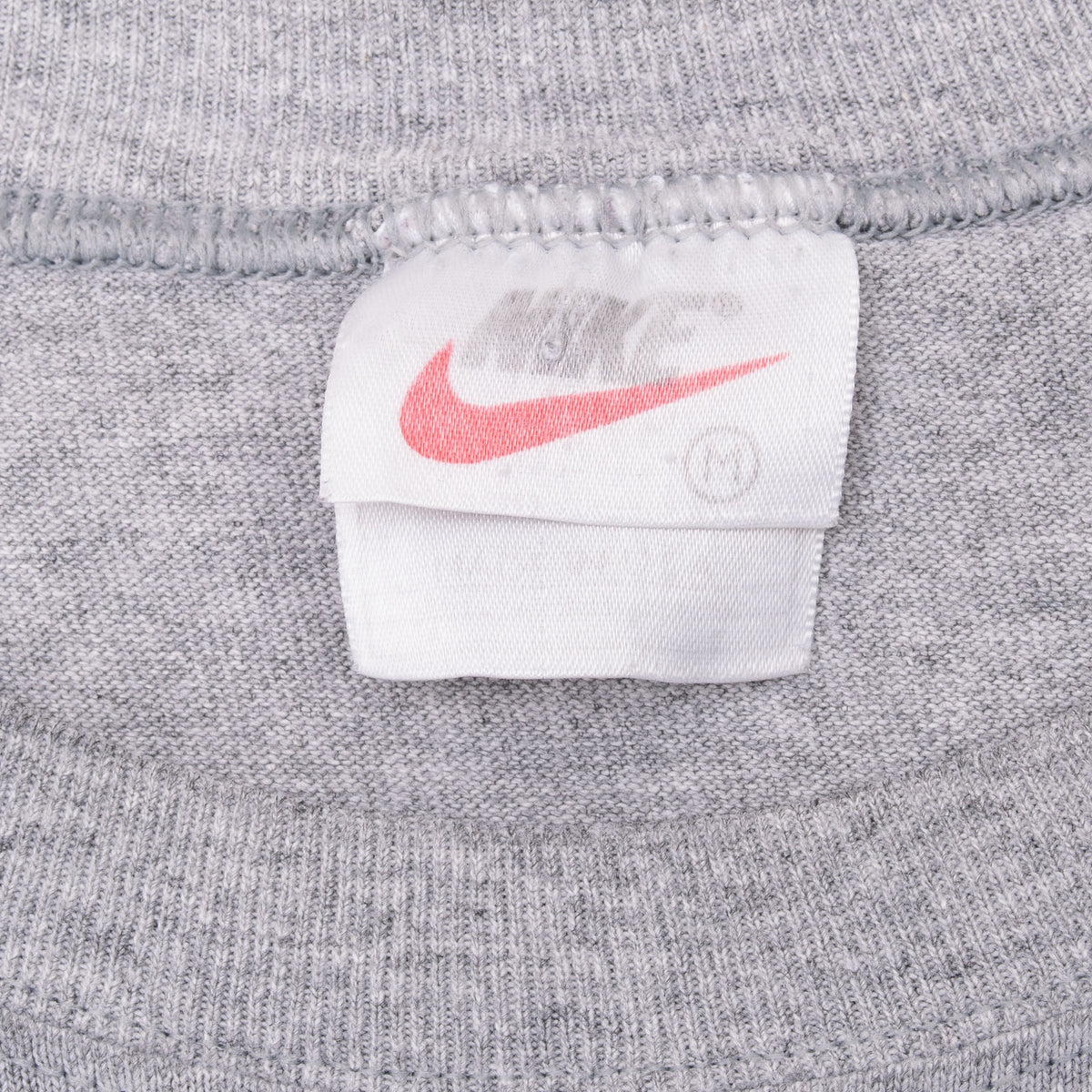 Close-up of Nike neck tag and ribbed crew neckline on grey tank top