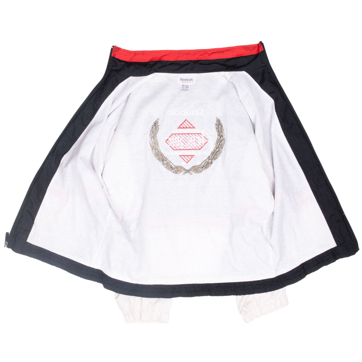 Interior of open Reebok windbreaker showing white lining and reverse of embroidered back graphic