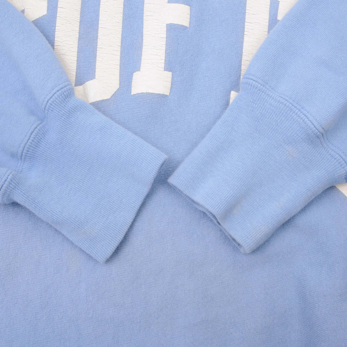 Close-up of ribbed blue sweatshirt cuffs and fabric below Tufts print
