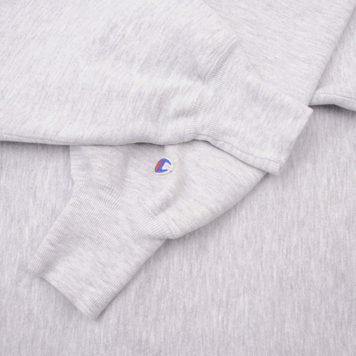 Champion embroidered sleeve logo and ribbed cuff detail on grey sweatshirt