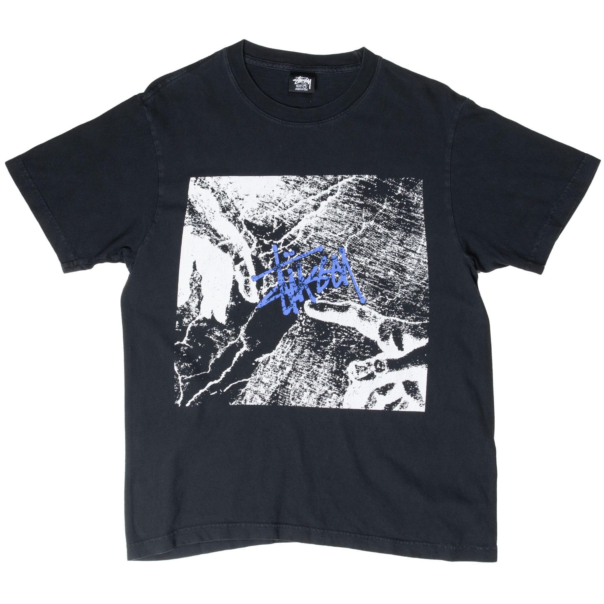 Full front of black Stüssy T-shirt with black-and-white graphic and blue script logo