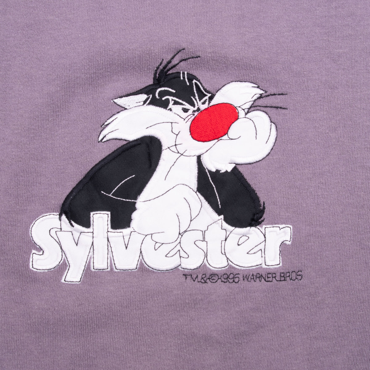 Close-up of Sylvester character and name embroidered on purple sweatshirt