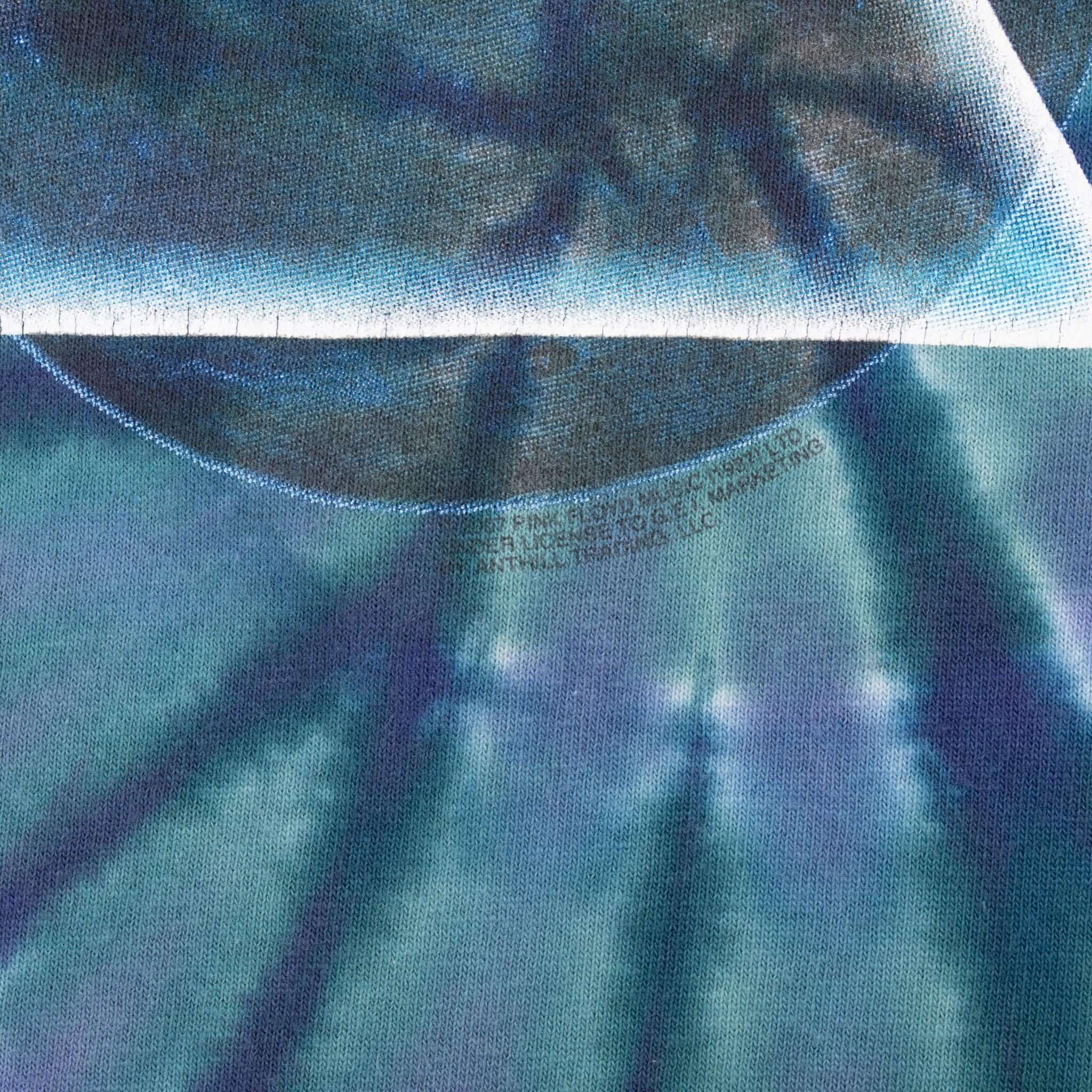 Close-up of faint printed text beneath the Pink Floyd prism graphic