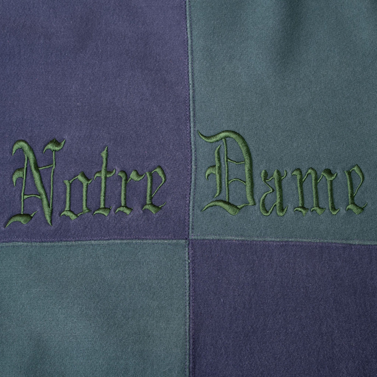 Close-up of green Gothic Notre Dame embroidery on the navy and green quartered front