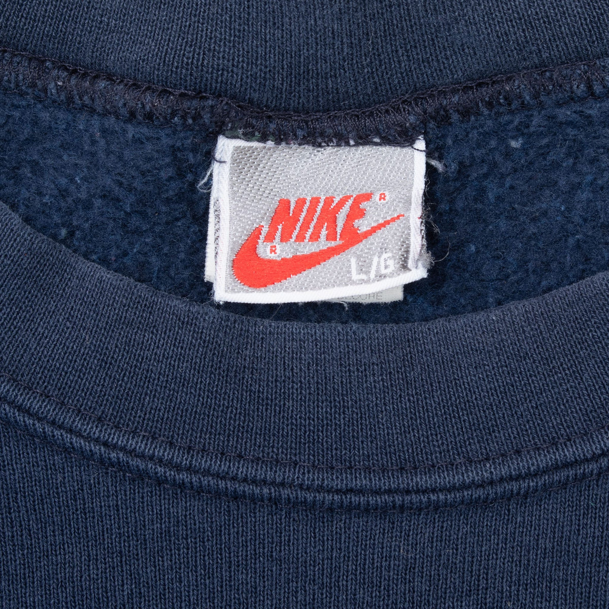 Close-up of Nike neck tag marked L/G inside navy sweatshirt collar