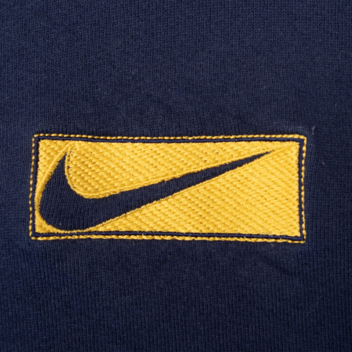 Close-up of rectangular yellow and navy Nike Swoosh chest patch
