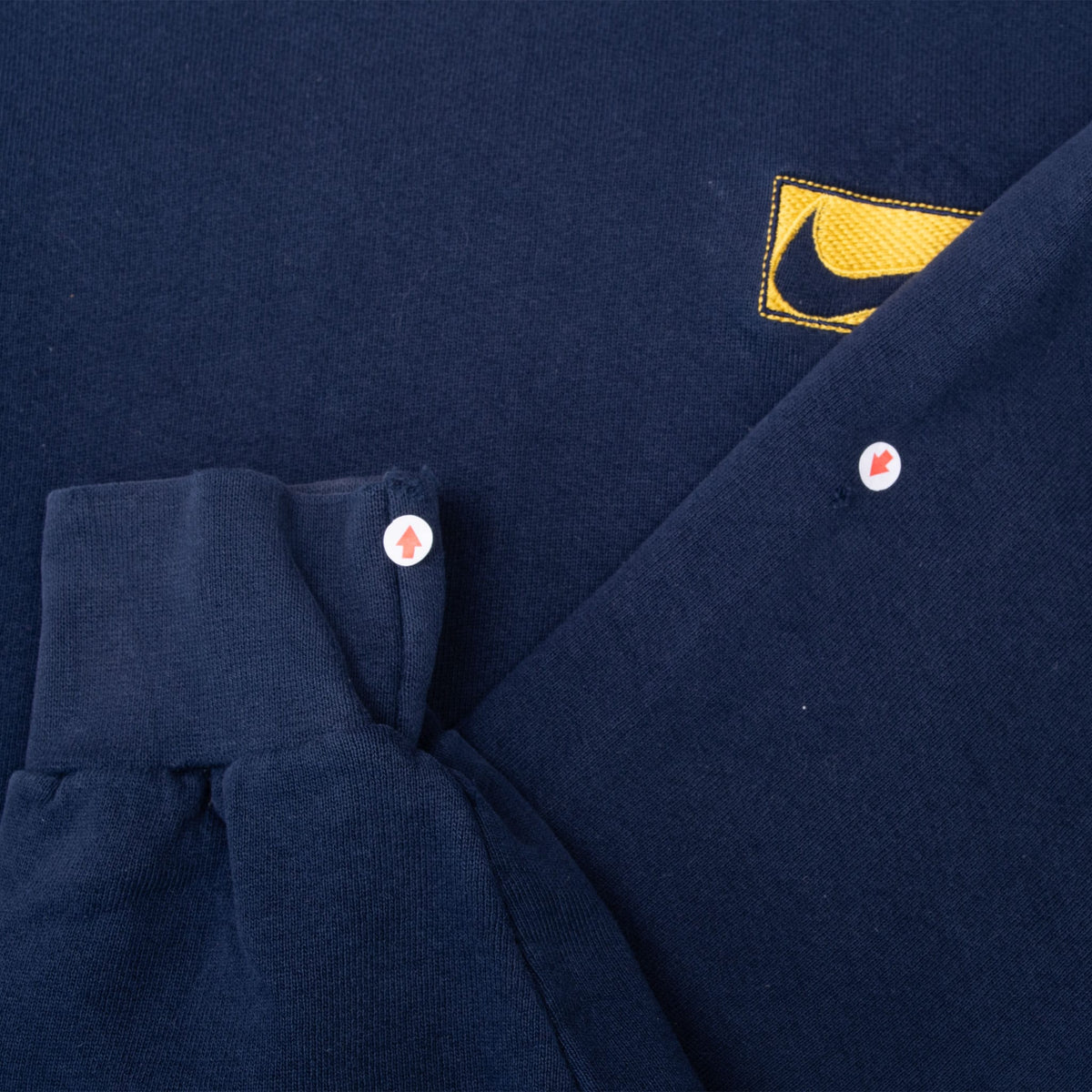 Close-up of navy sweatshirt sleeves with markers indicating small surface spots