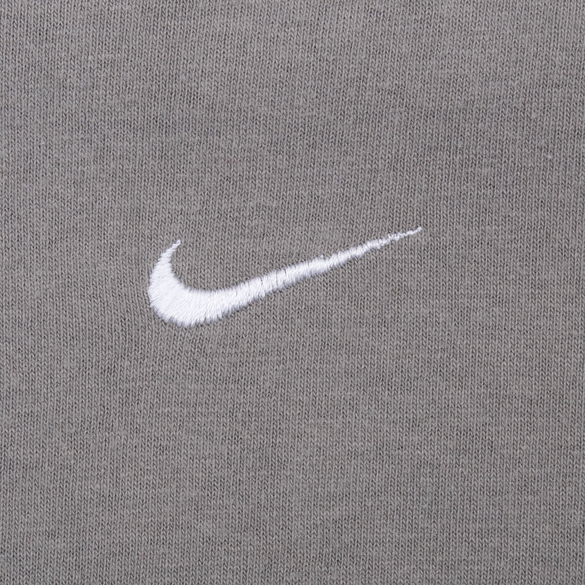 Close-up of white embroidered Nike Swoosh on grey chest fabric
