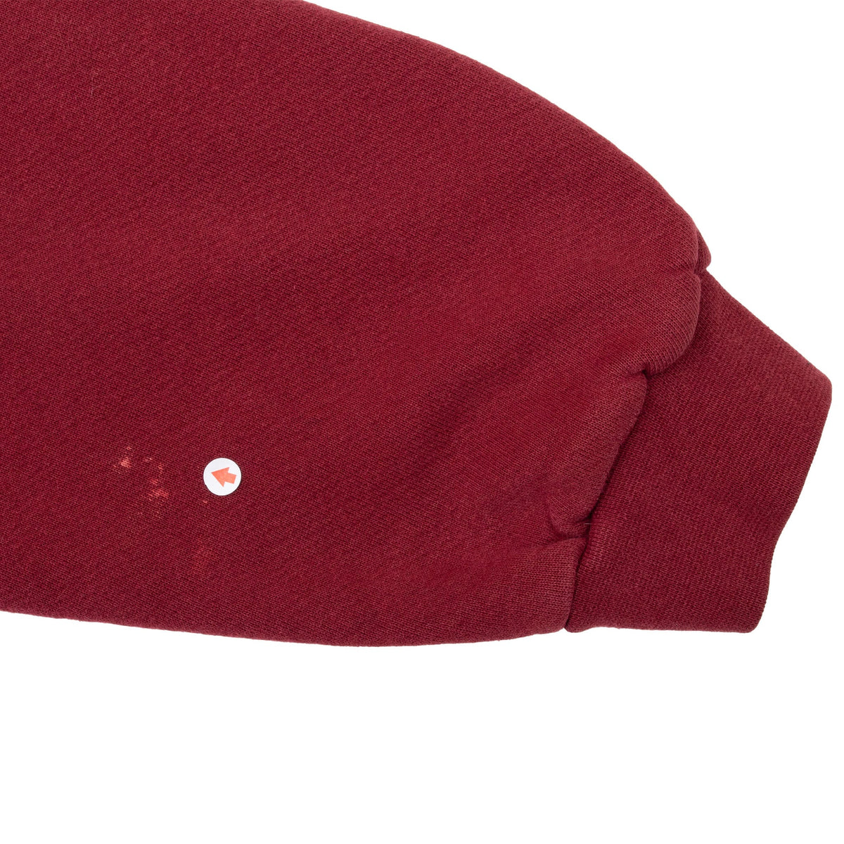 Close-up of burgundy sweatshirt sleeve showing small marks near the ribbed cuff