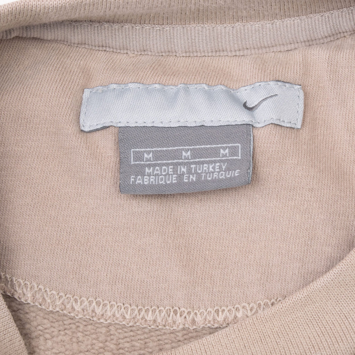 Close-up of Nike medium neck label inside beige sweatshirt