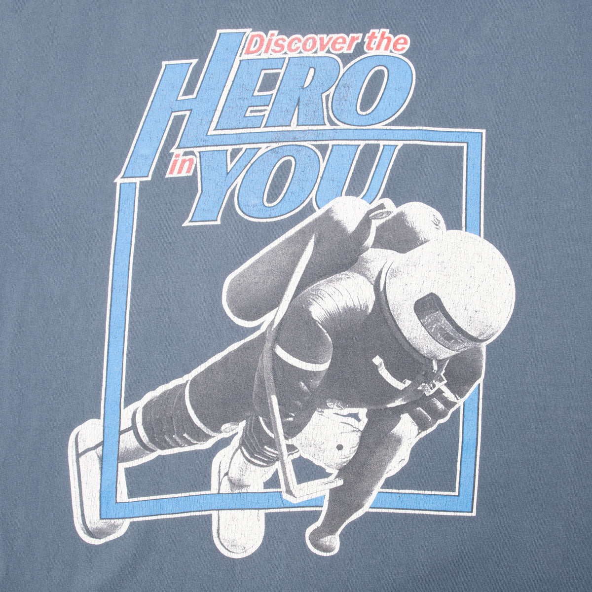 Close-up of “Discover the Hero in You” hockey graphic on blue T-shirt