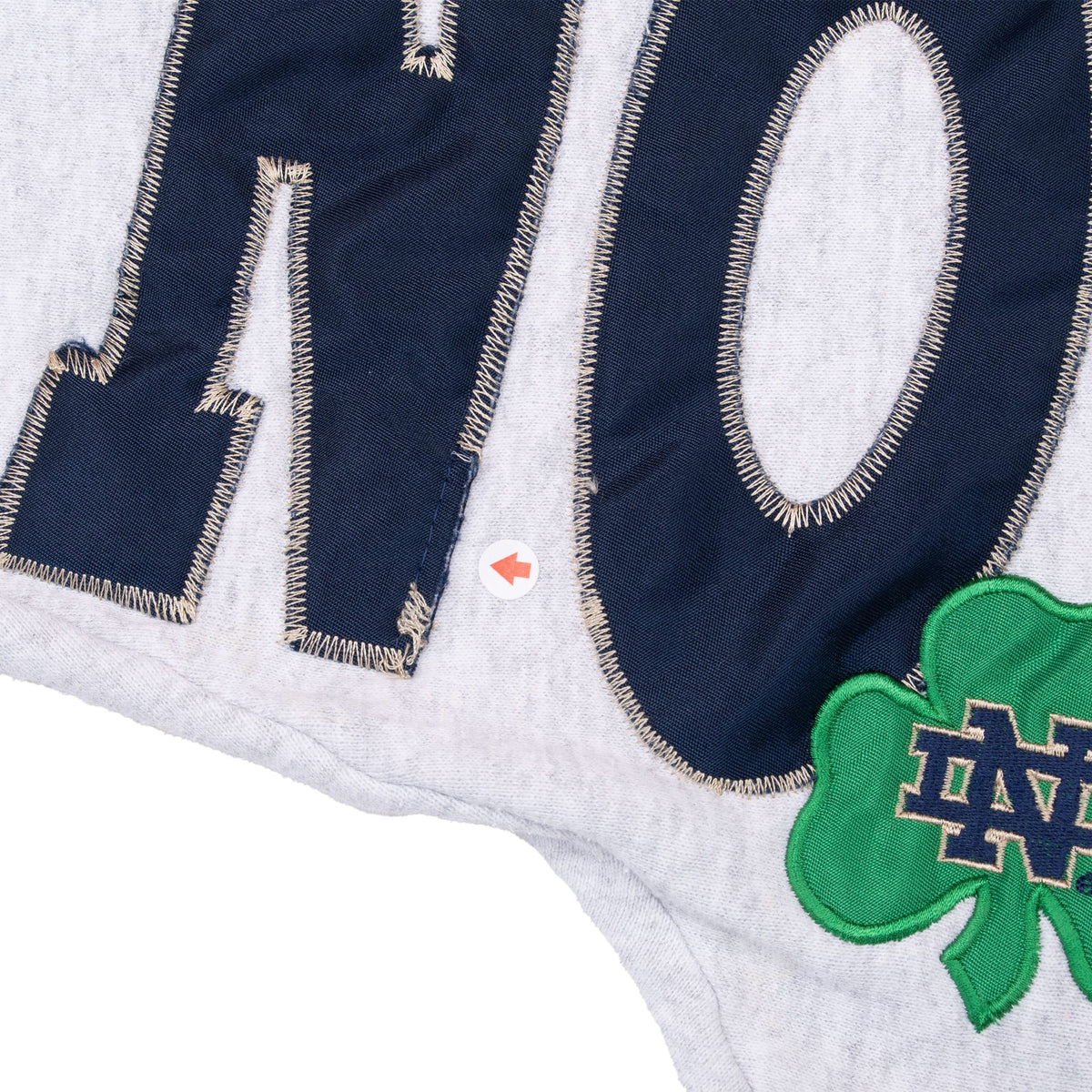 Close-up of navy appliqué lettering, green ND shamrock and marked fabric spot