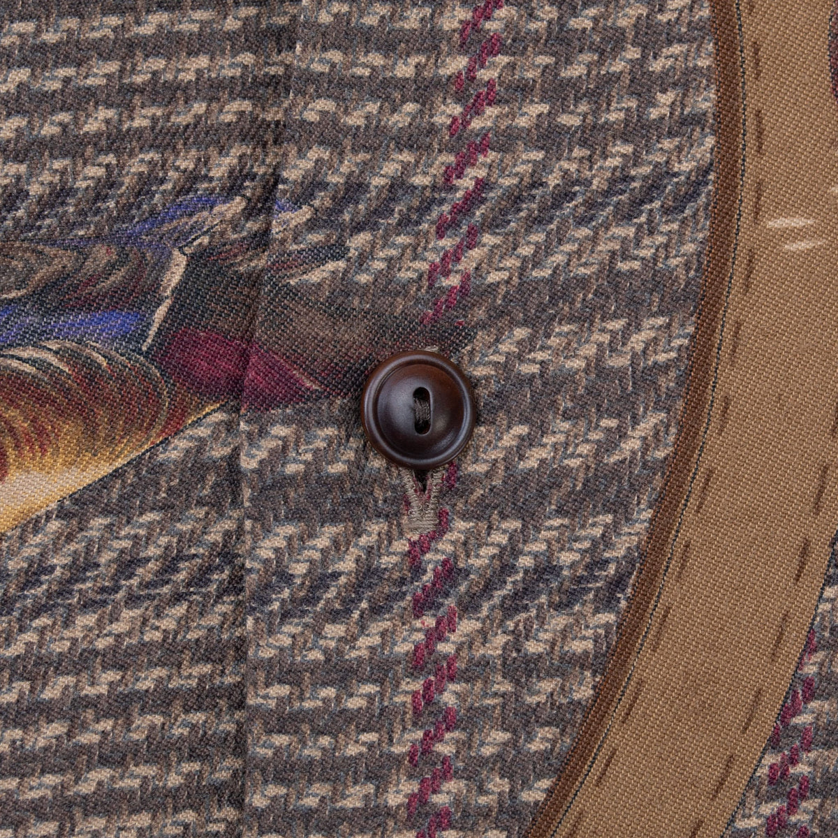 Close-up of dark brown front button, plaid fabric, duck print, and strap detail