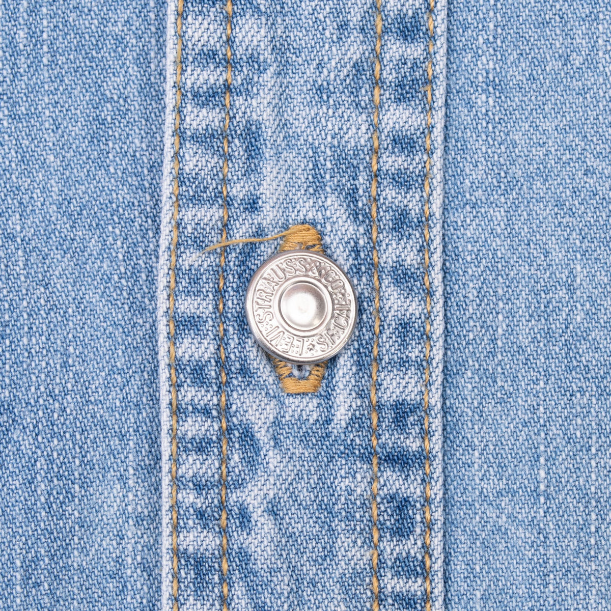 Close-up of engraved Levi Strauss metal button and contrast stitching
