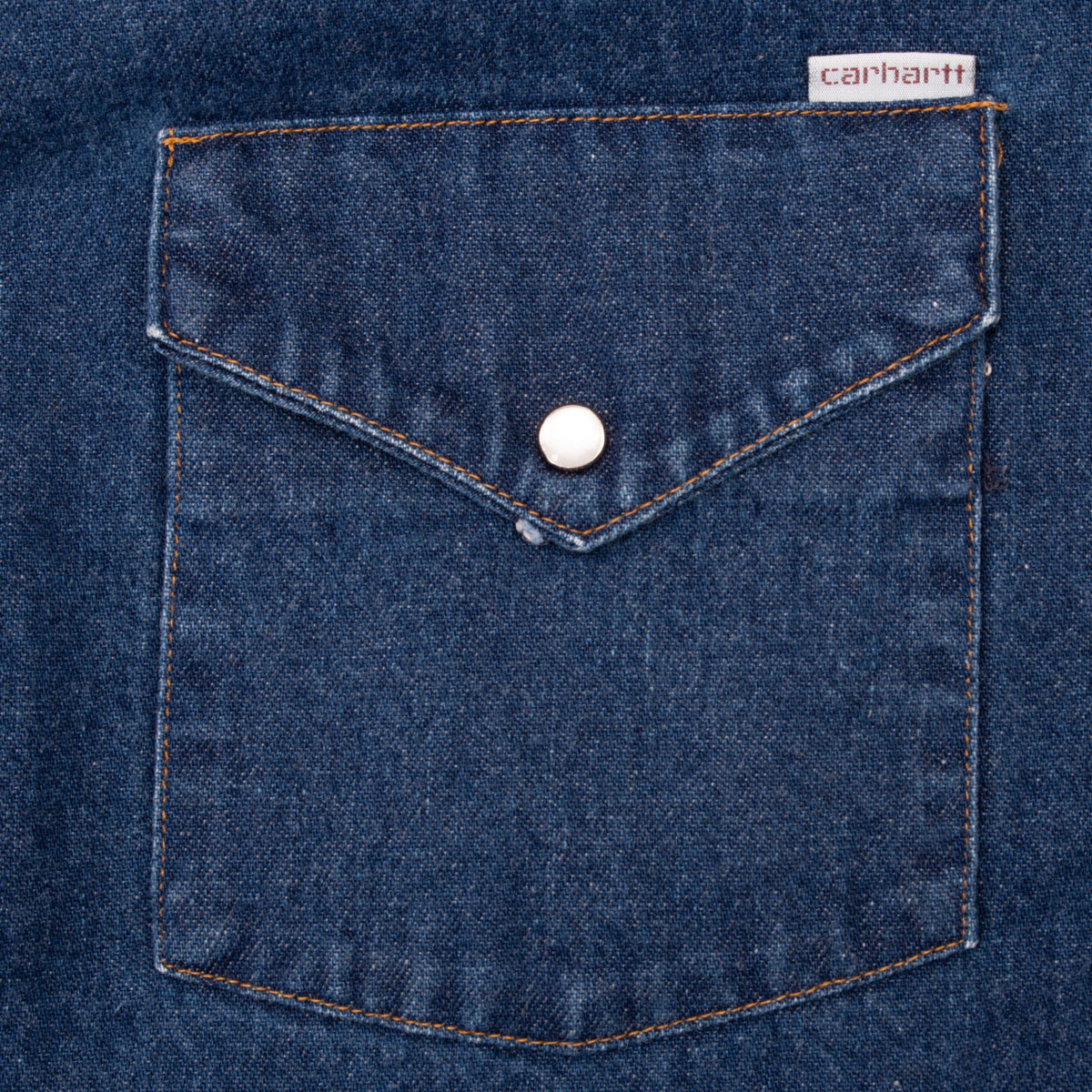 Carhartt denim chest pocket with pointed flap, pearl snap, and contrast stitching