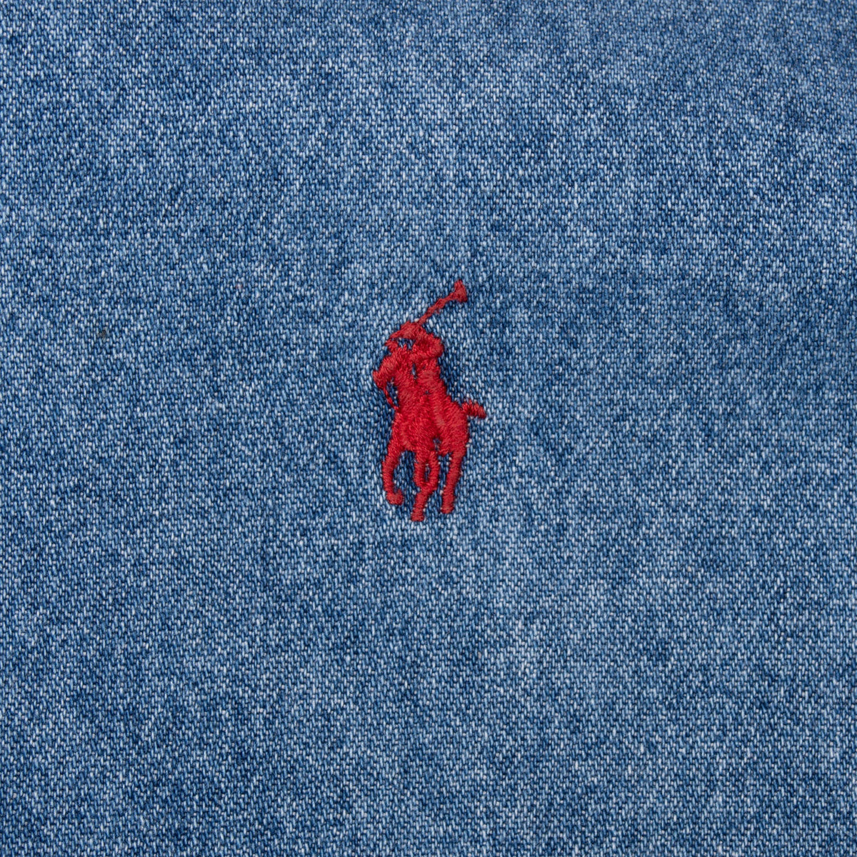 Close-up of red Polo pony logo embroidered on blue denim shirt