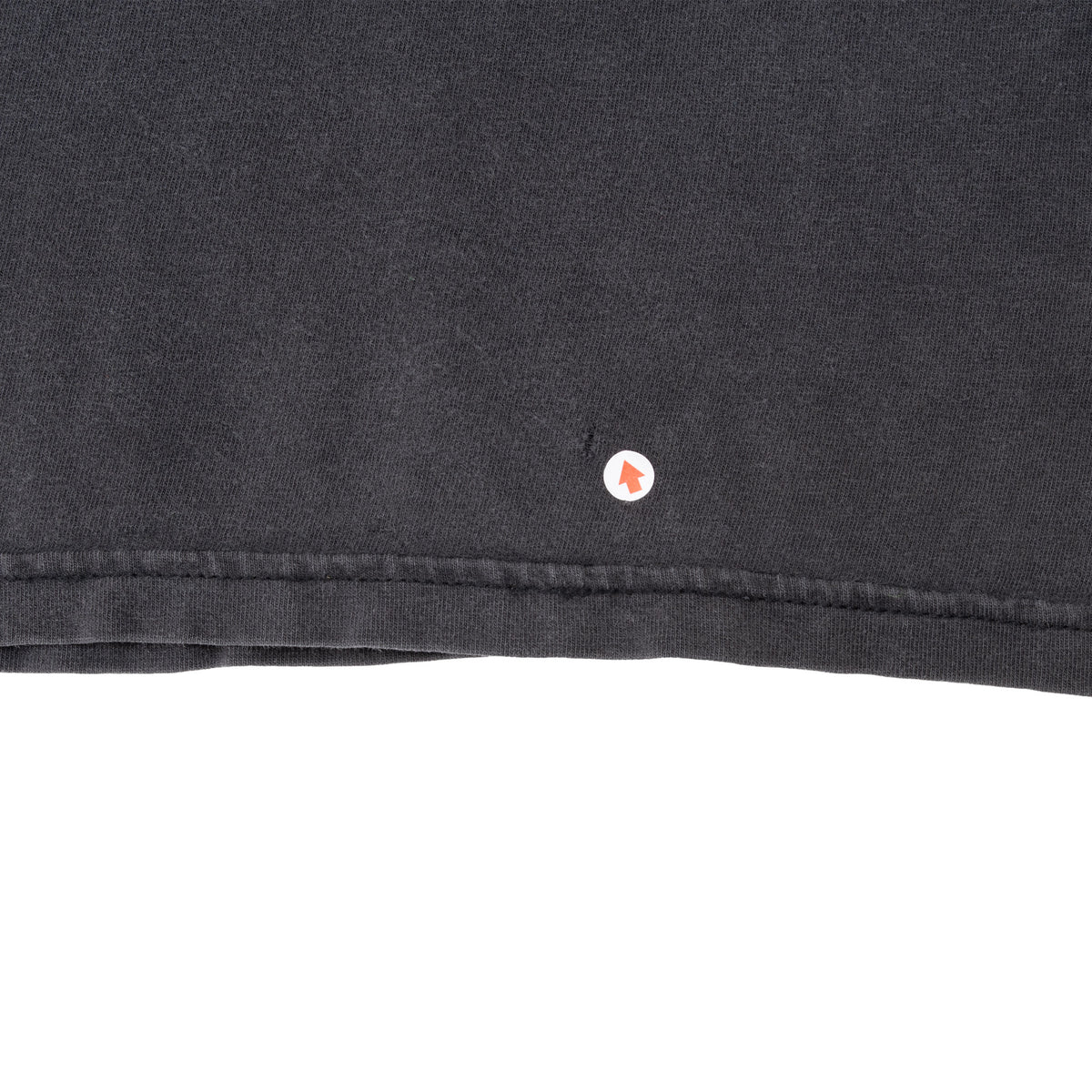 Close-up of a small hole above the bottom hem of the black shirt