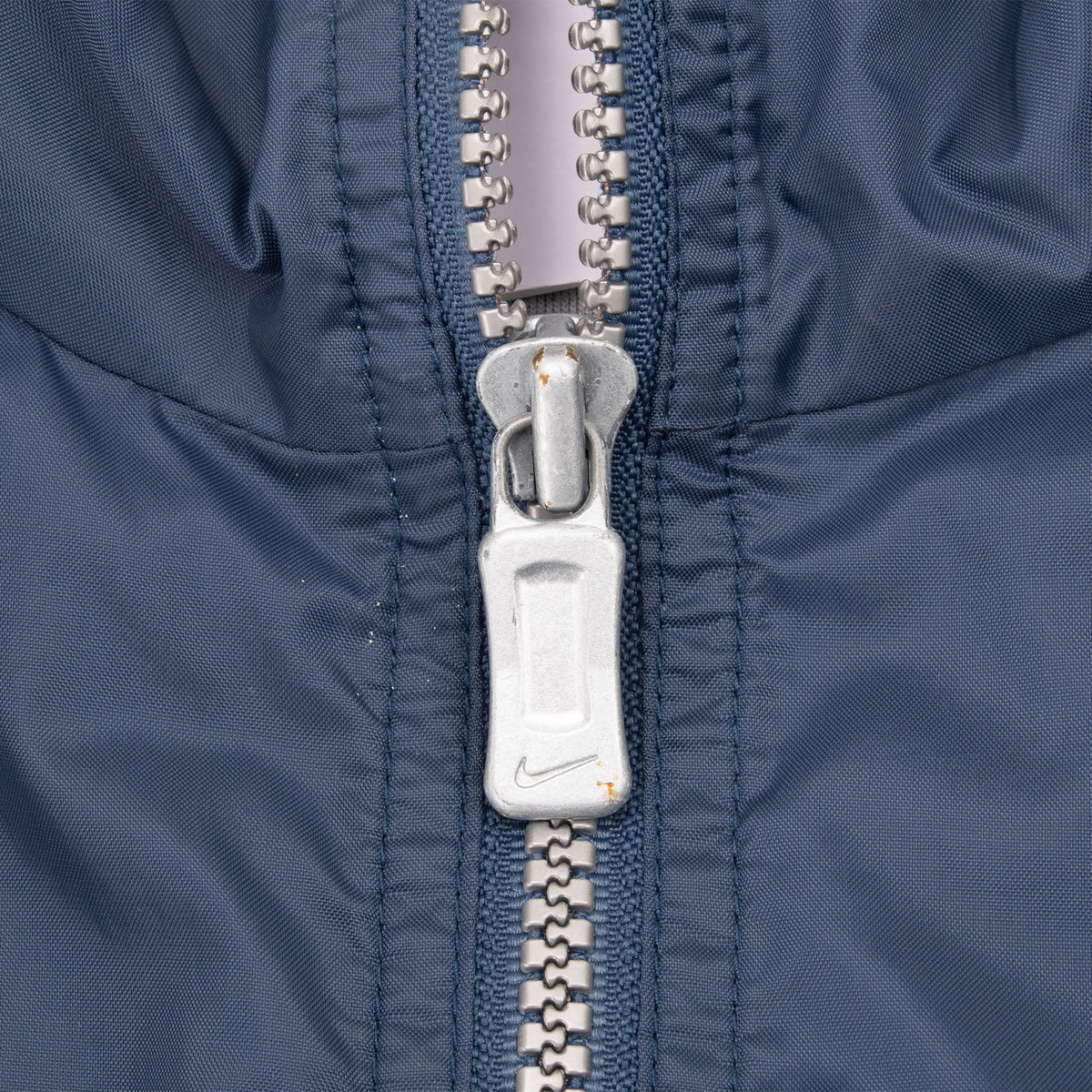 Close-up of silver Nike zipper pull on navy blue windbreaker