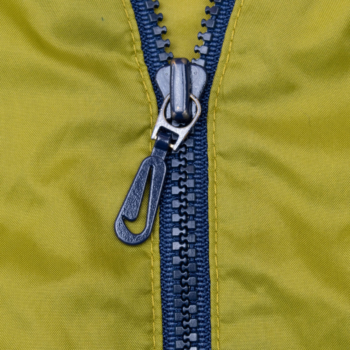 Close-up of navy half-zip closure on the green front panel
