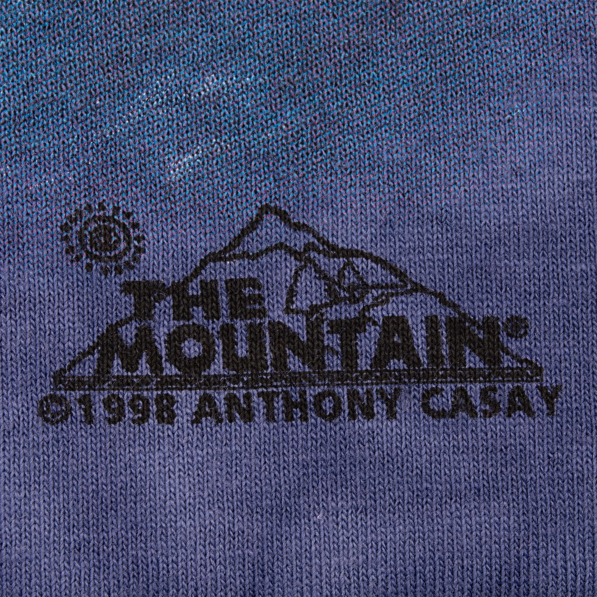 Close-up of The Mountain logo and 1998 copyright print on blue fabric