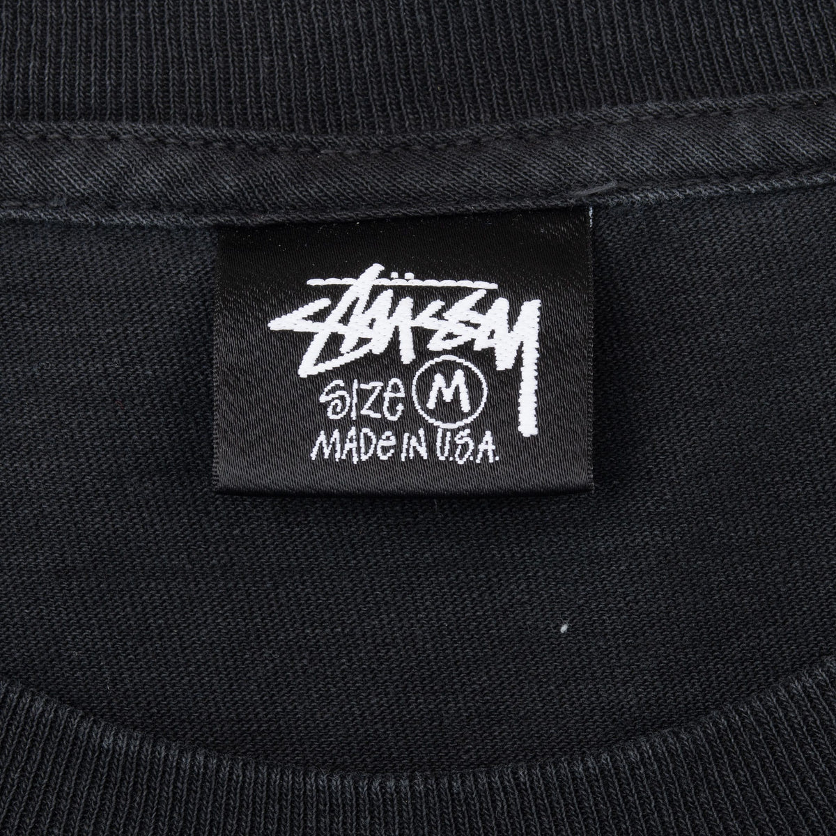 Stüssy neck tag marked size M and Made in U.S.A.