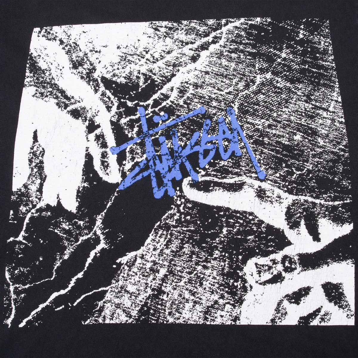 Close-up of black-and-white chest print with blue Stüssy script logo