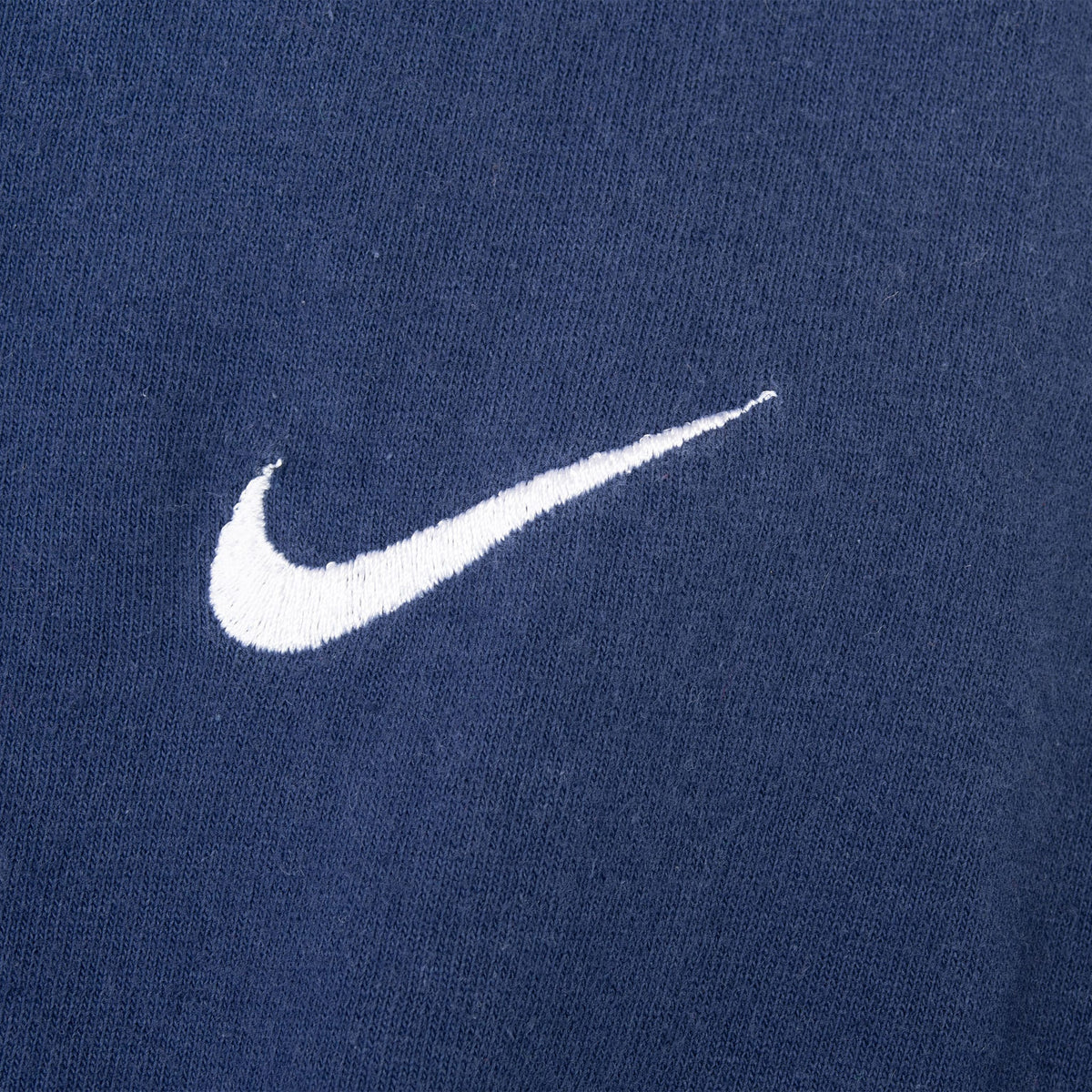 Close-up of white embroidered Nike Swoosh on navy blue fabric
