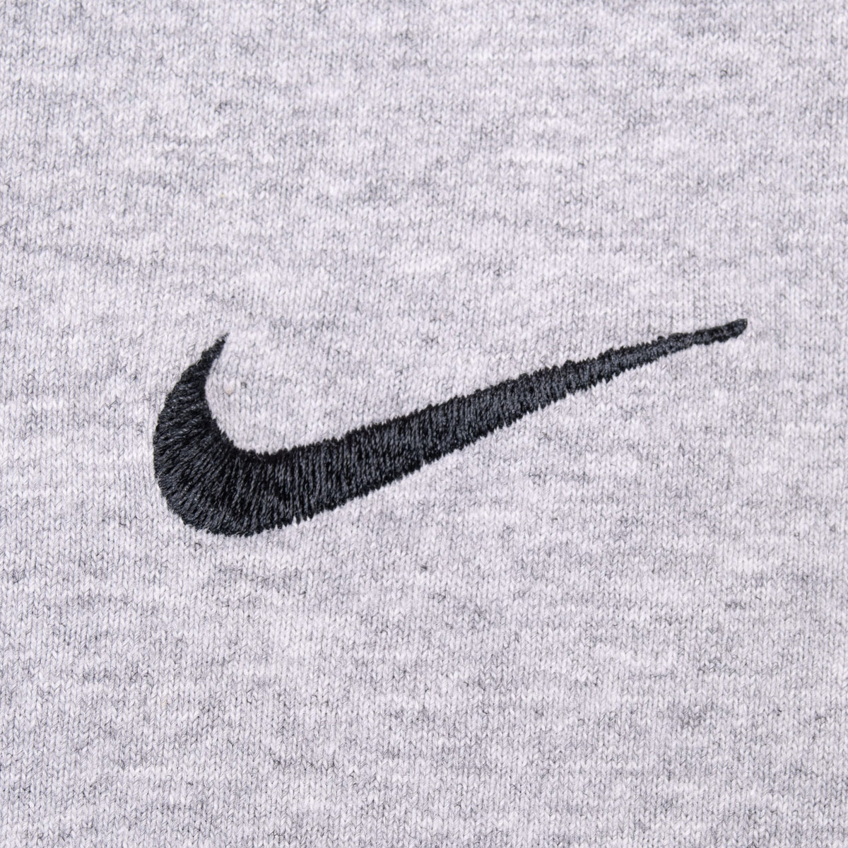Close-up of black embroidered Nike Swoosh on heather grey fabric