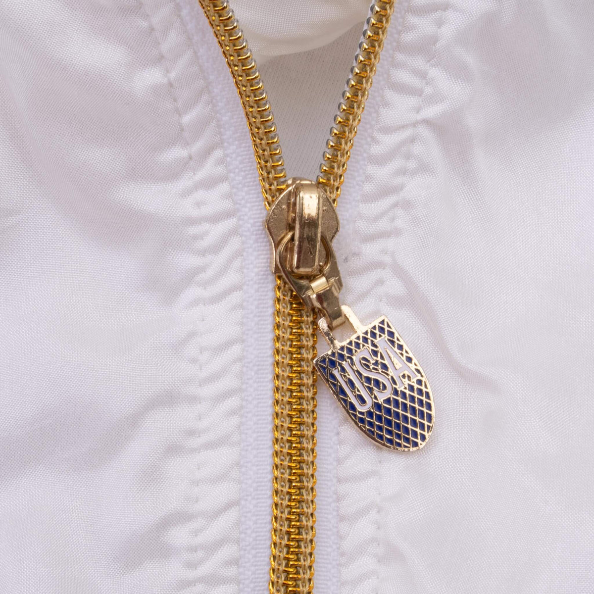 Close-up of gold jacket zipper with blue and gold USA shield pull