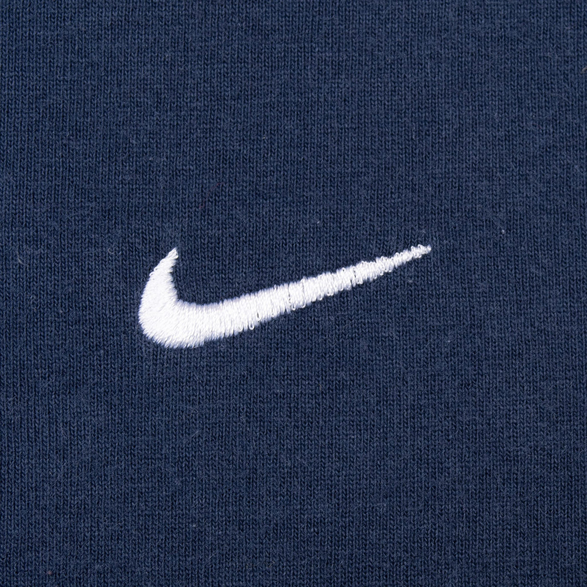 Close-up of white embroidered Nike Swoosh on navy blue fabric