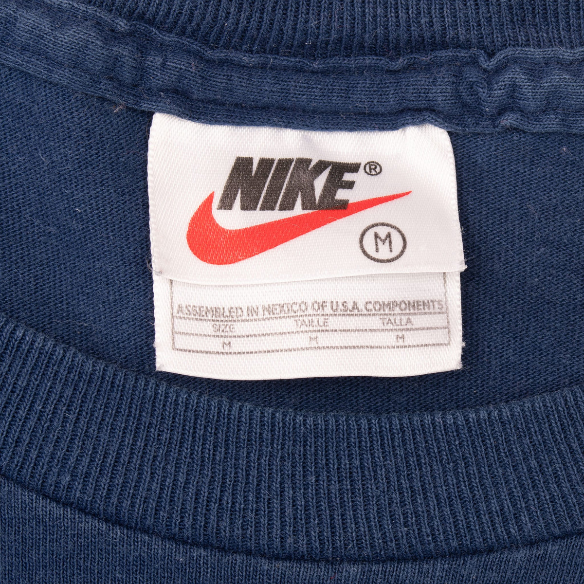 Close-up of Nike neck tag marked size medium inside blue ribbed crew collar