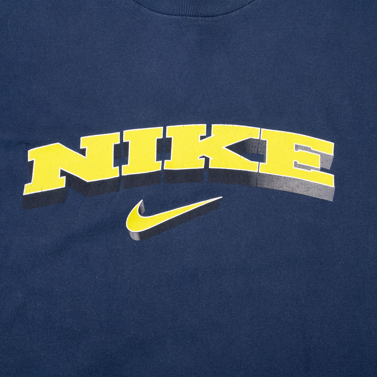 Close-up of yellow Nike spellout and Swoosh front graphic with white outline and dark shadow