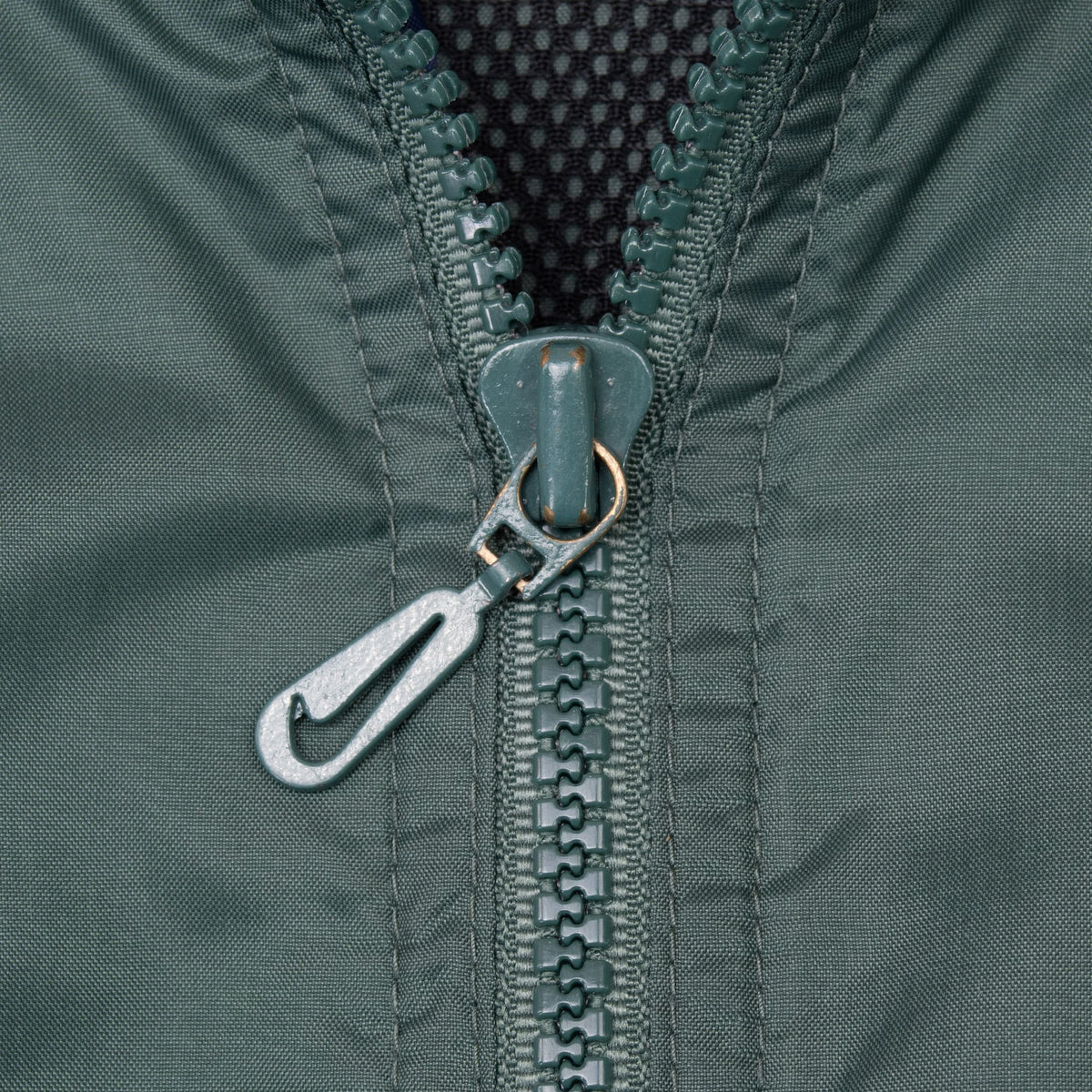 Close-up of green front zipper with Swoosh-shaped metal pull