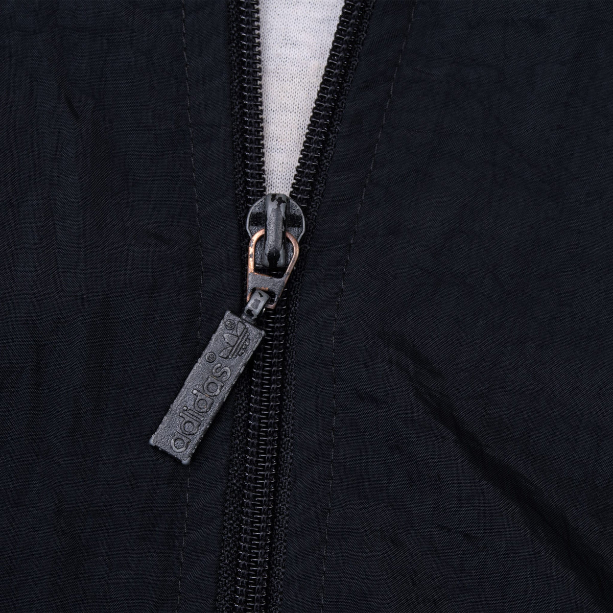 Close-up of black front zipper with embossed Adidas pull