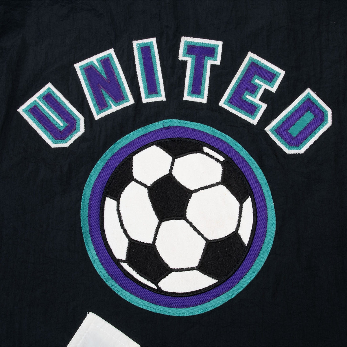 Close-up of United soccer ball back emblem in purple, teal, black, and white