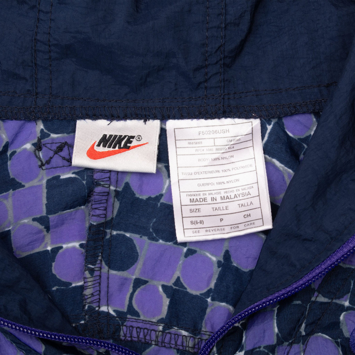 Interior Nike brand and care labels on purple and navy dotted jacket