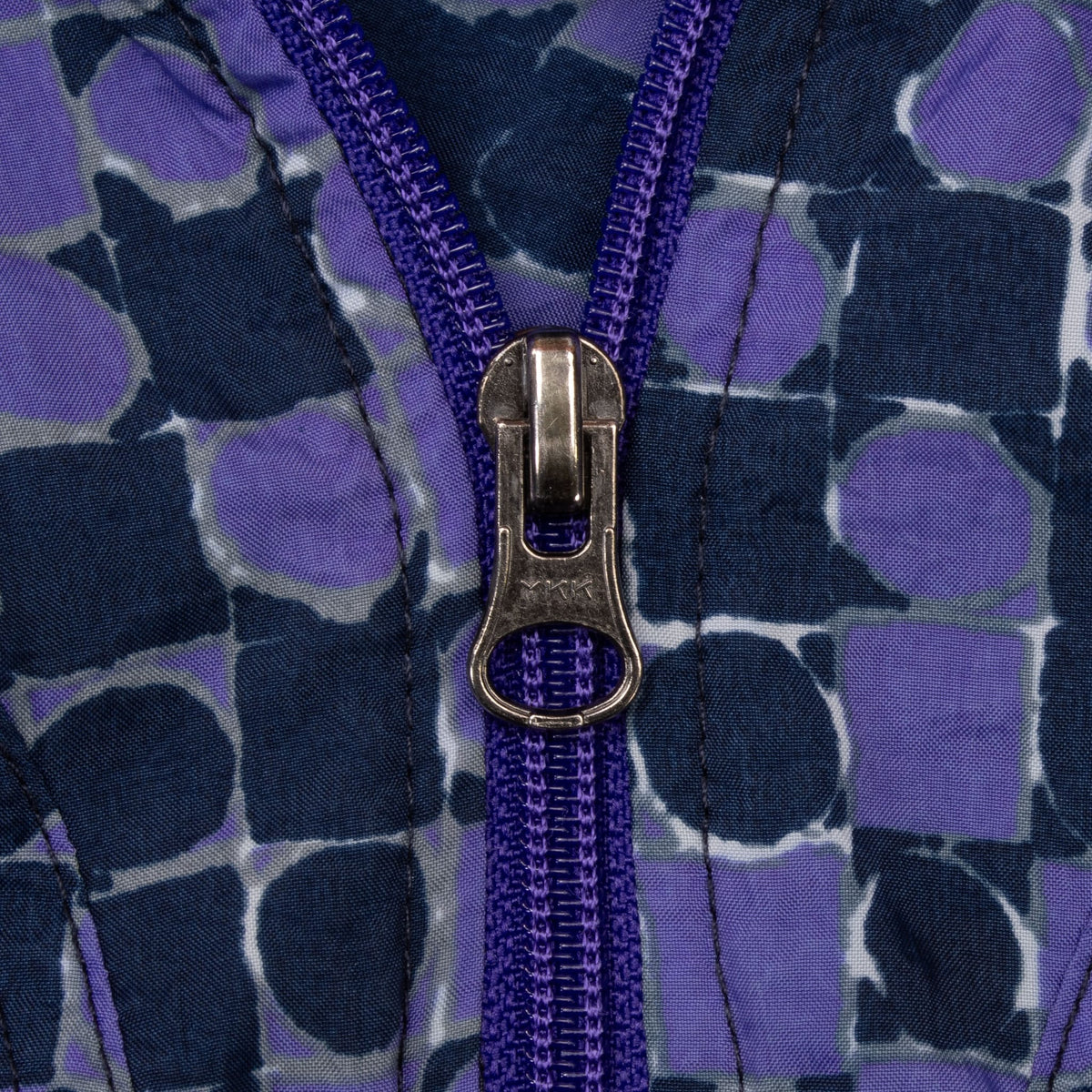 Close-up of metal quarter-zip pull and purple zipper on dotted Nike jacket