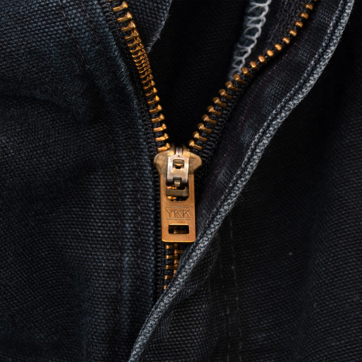 Close-up of brass-tone YKK zip fly on black Carhartt pants