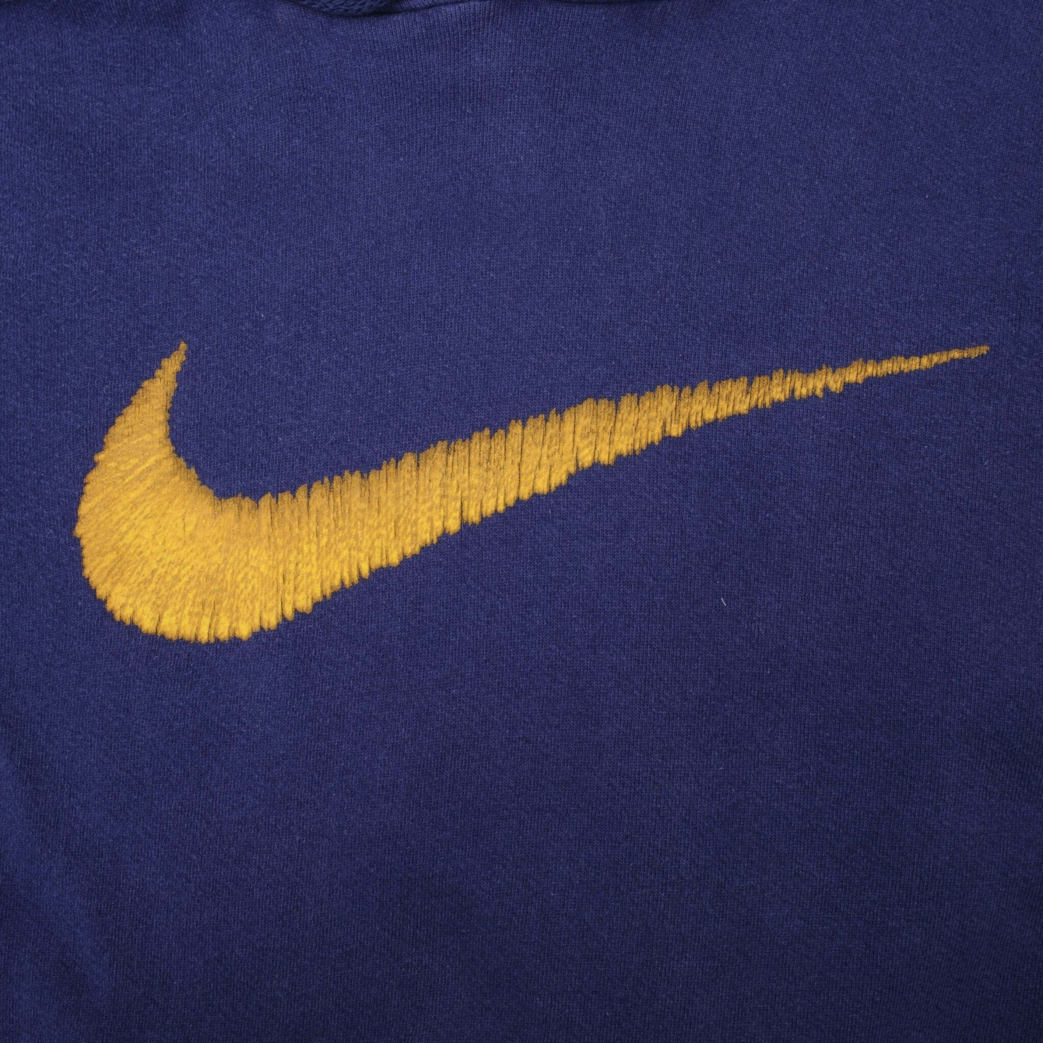 Close-up of large yellow Nike Swoosh embroidery on blue hoodie