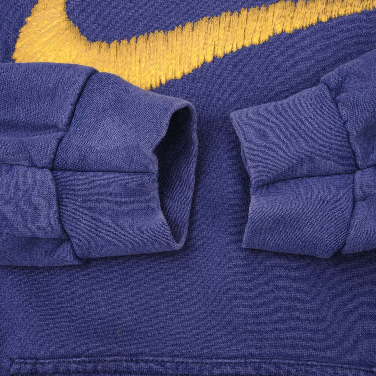 Close-up of blue hoodie sleeve cuffs below yellow Swoosh embroidery