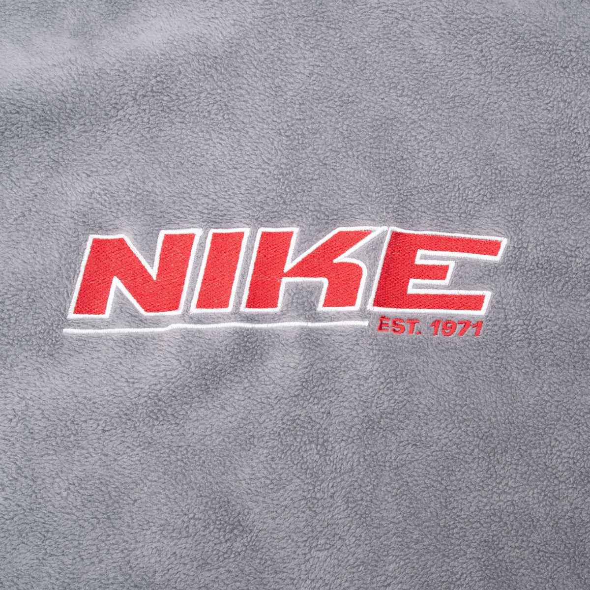 Close-up of red and white Nike EST. 1971 chest embroidery on grey fleece