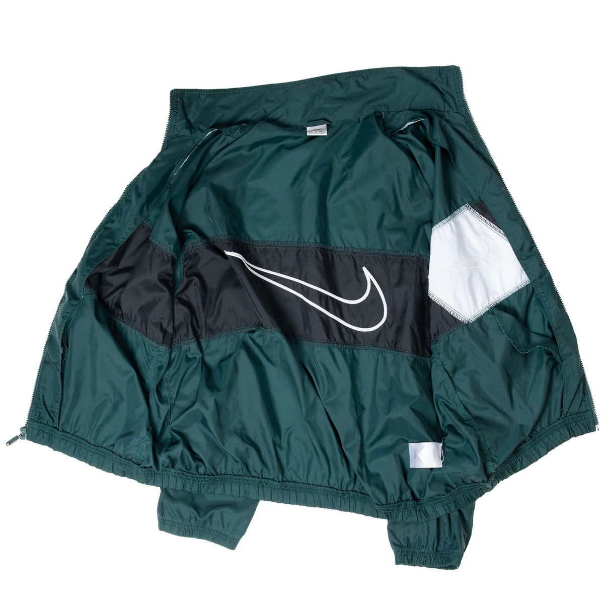 Interior view of open green Nike windbreaker showing reverse of color-blocked panels