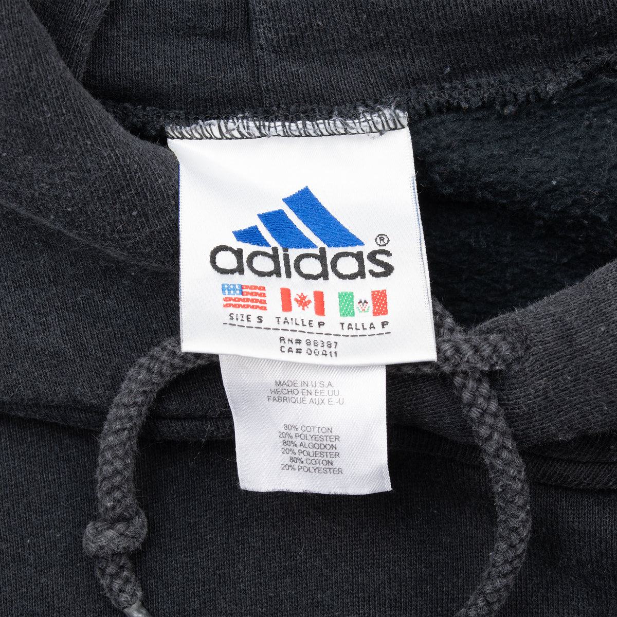 Close-up of Adidas size small neck and care labels inside black hoodie