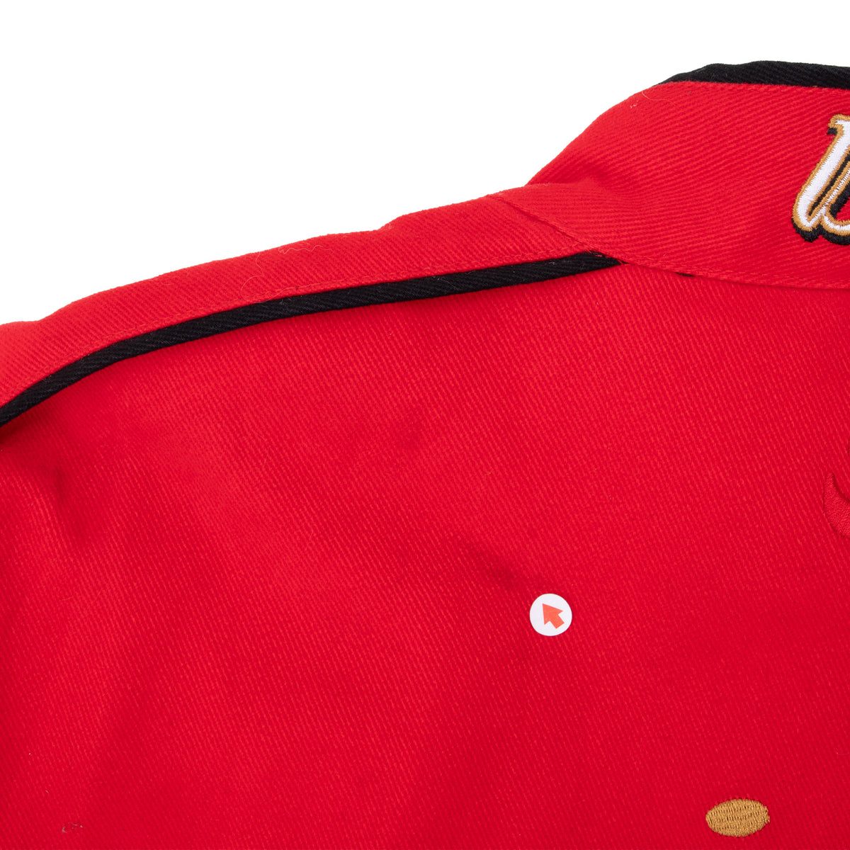 Close-up of red jacket shoulder and collar with black piping detail