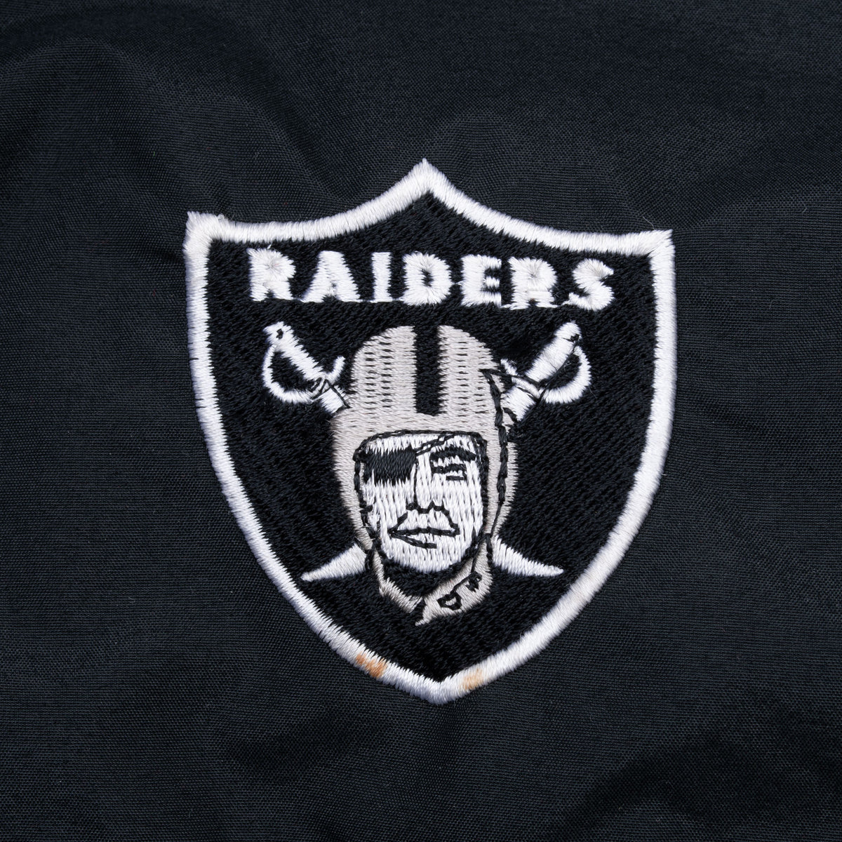 Close-up of embroidered Raiders shield logo on jacket chest