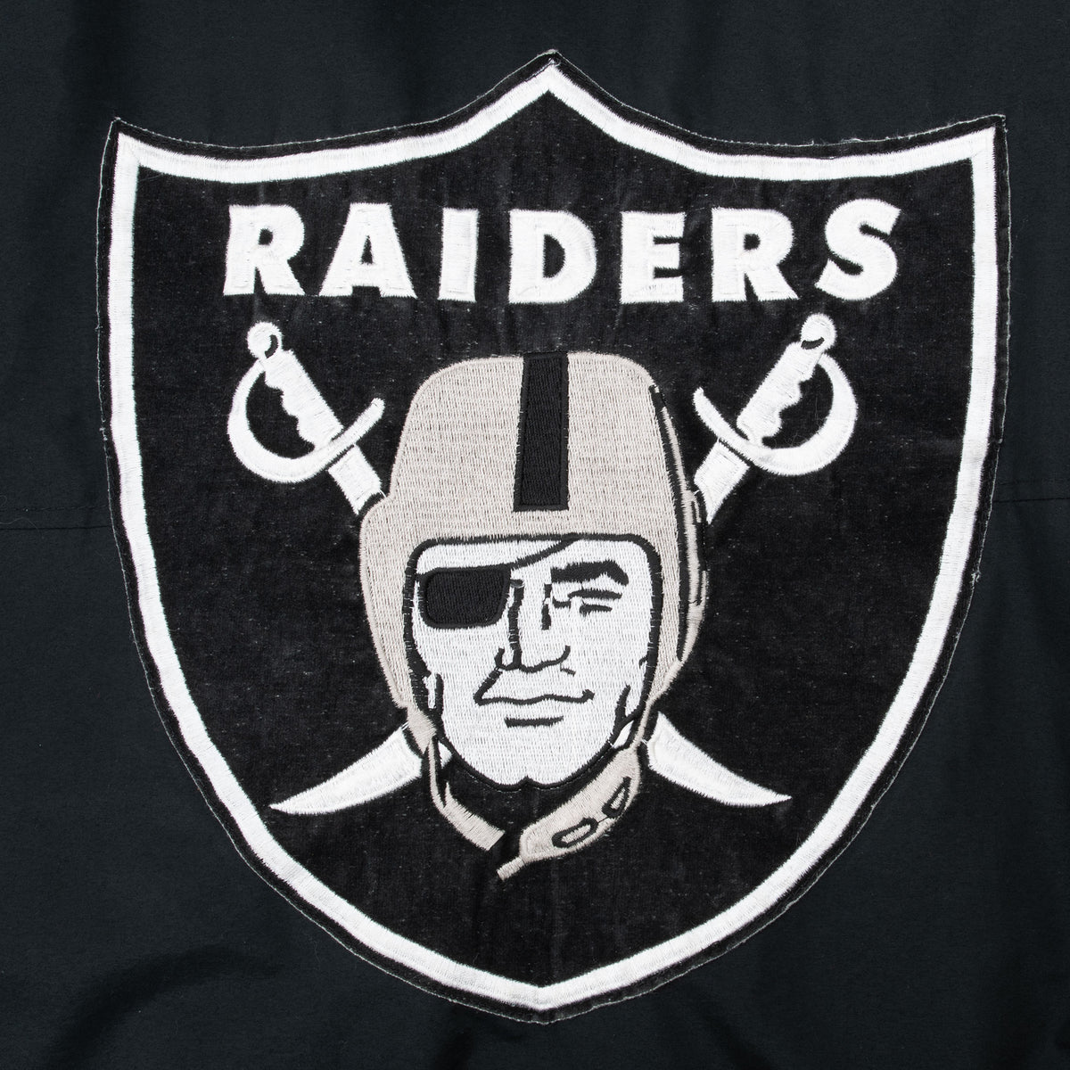 Close-up of large black-and-white Raiders shield embroidery on jacket back