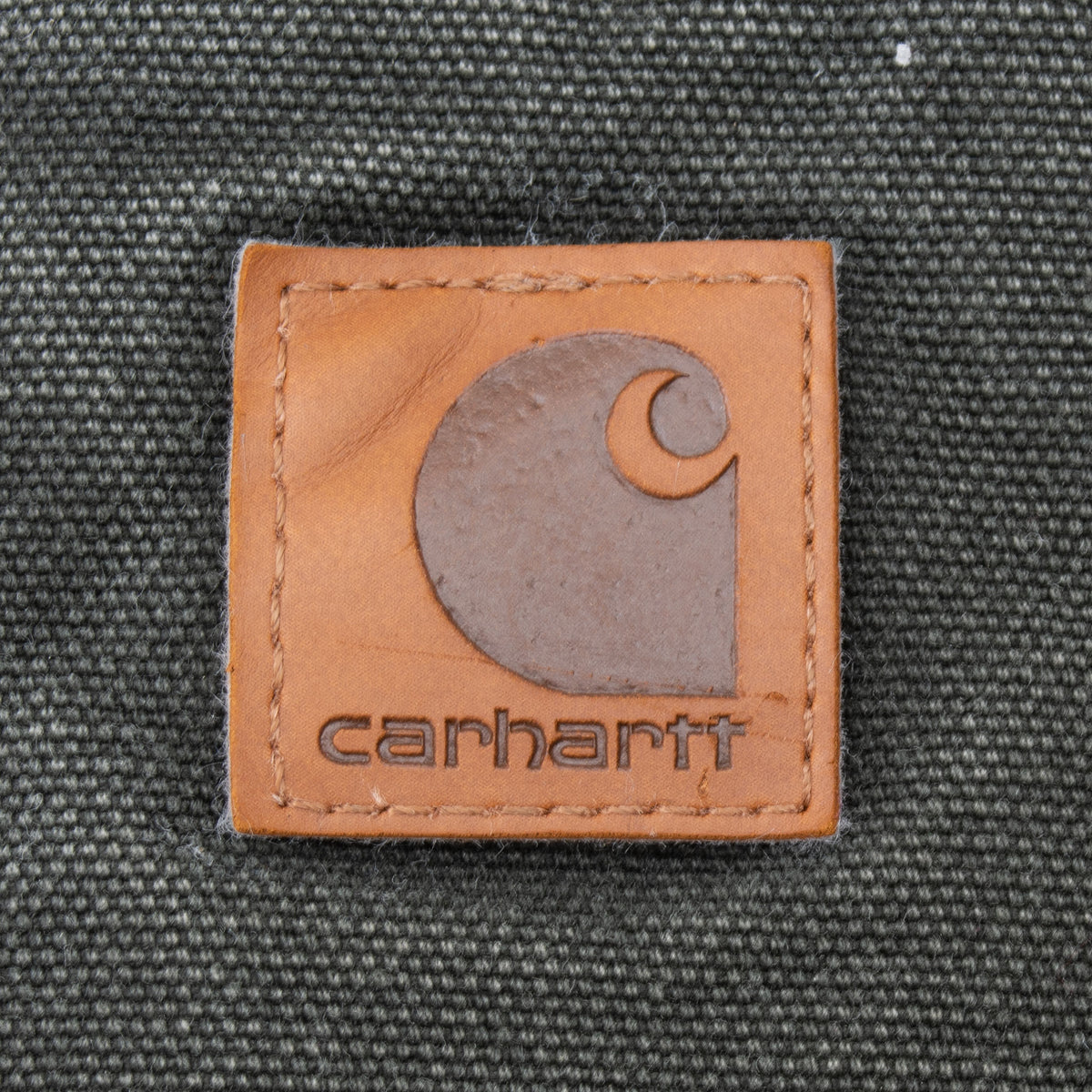 Close-up of square Carhartt logo patch on green vest fabric
