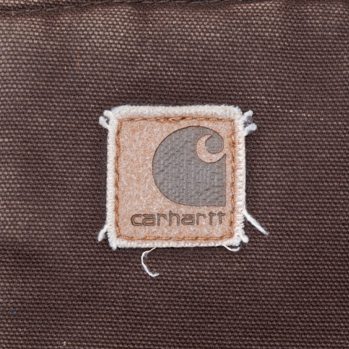Close-up of Carhartt logo patch on the brown vest pocket