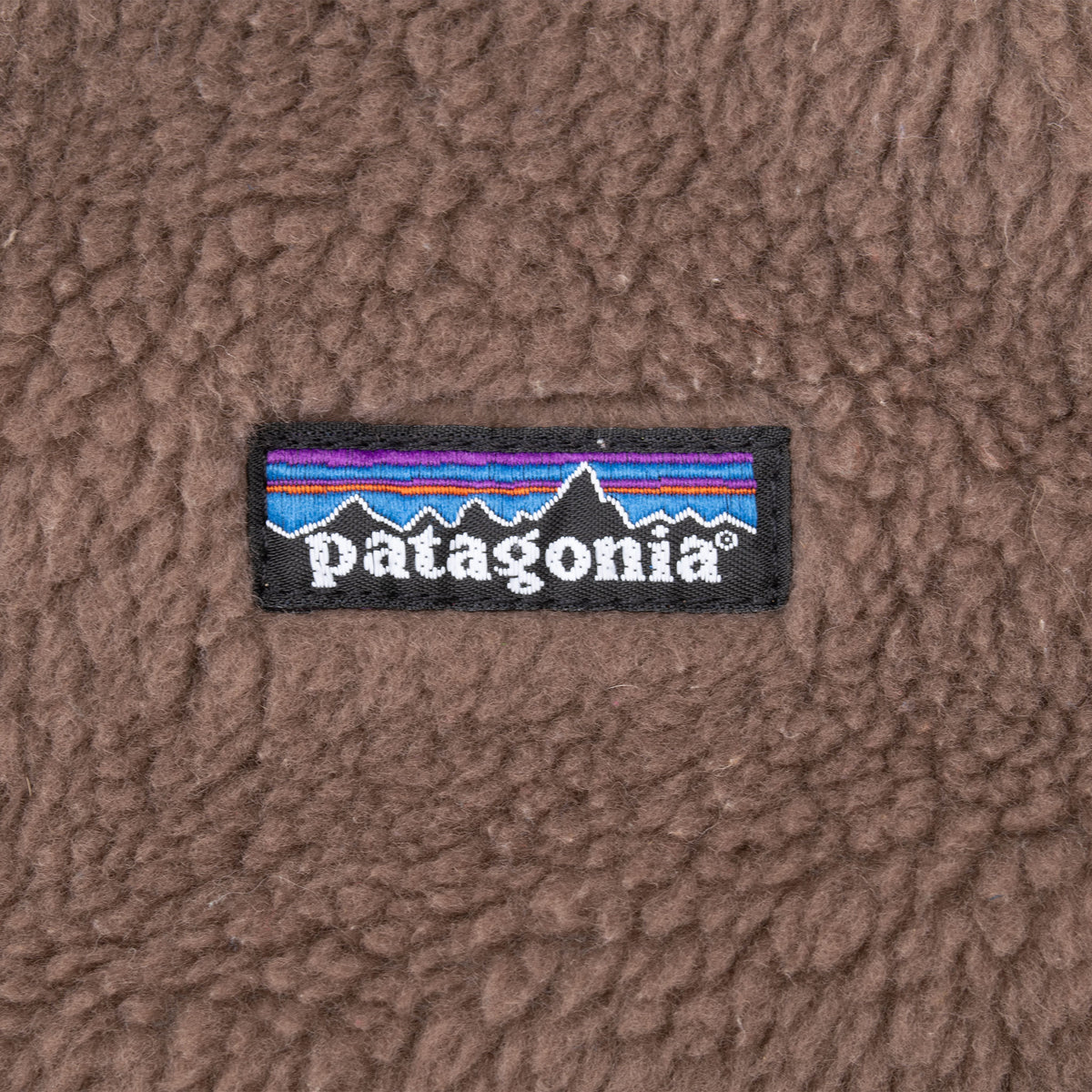 Close-up of embroidered Patagonia logo patch on brown fleece